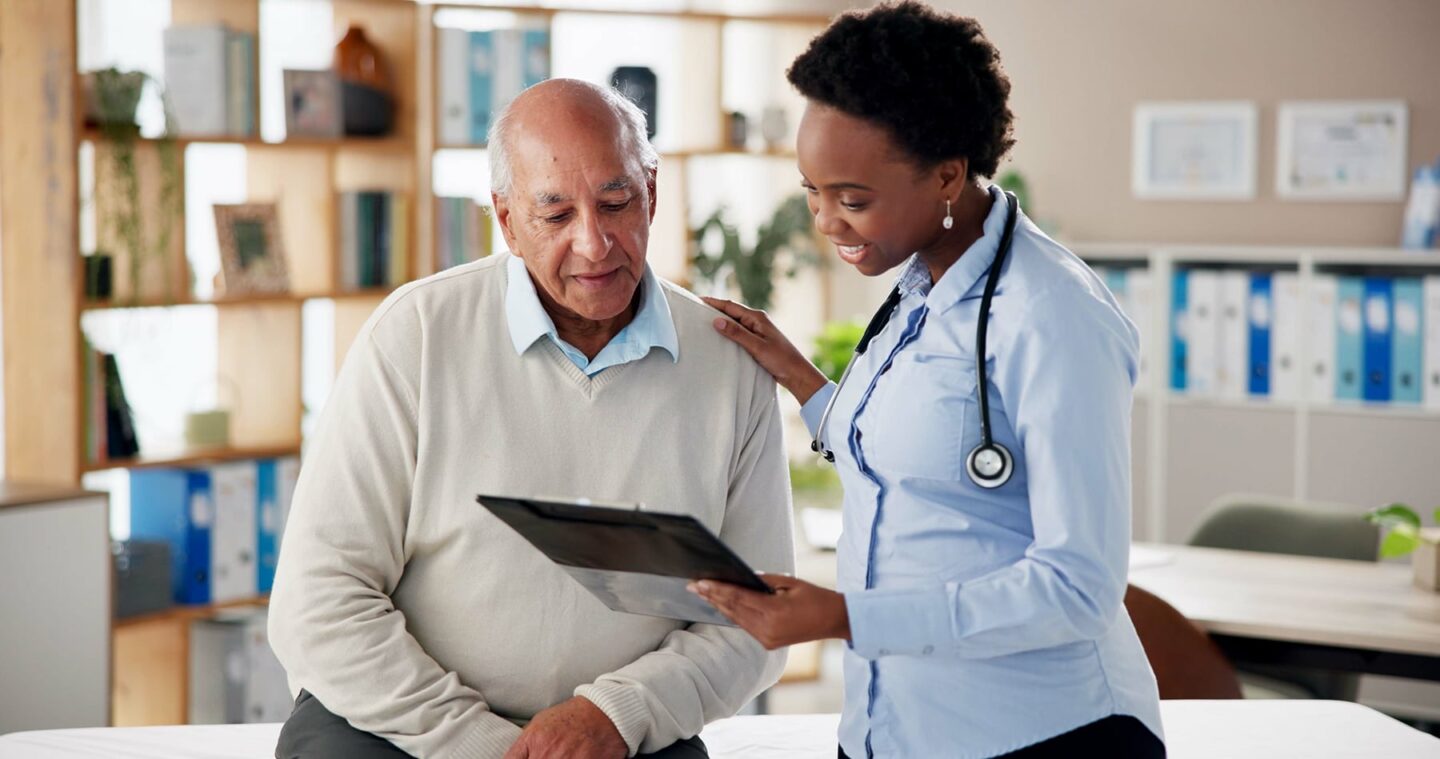 A patient and his female doctor in a room while she shows him good information on a tablet, explaining the gout kidney connection