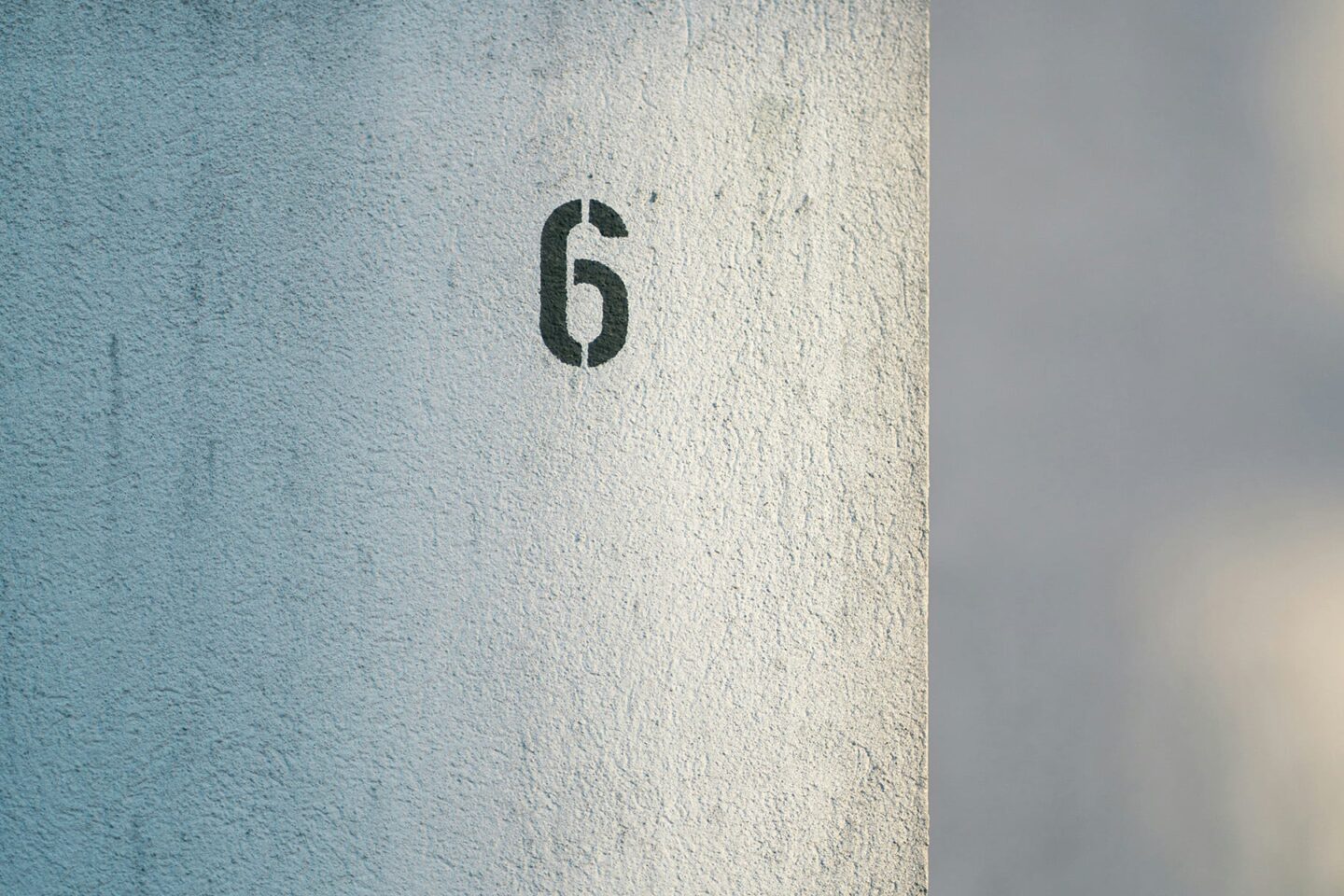 Concrete wall with a small black stencil of the letter 6, representing your gout target uric acid number, 6.0 mg/dL