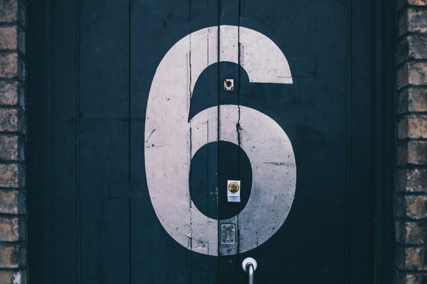 large stencil painting of the number 6 on navy alley doors