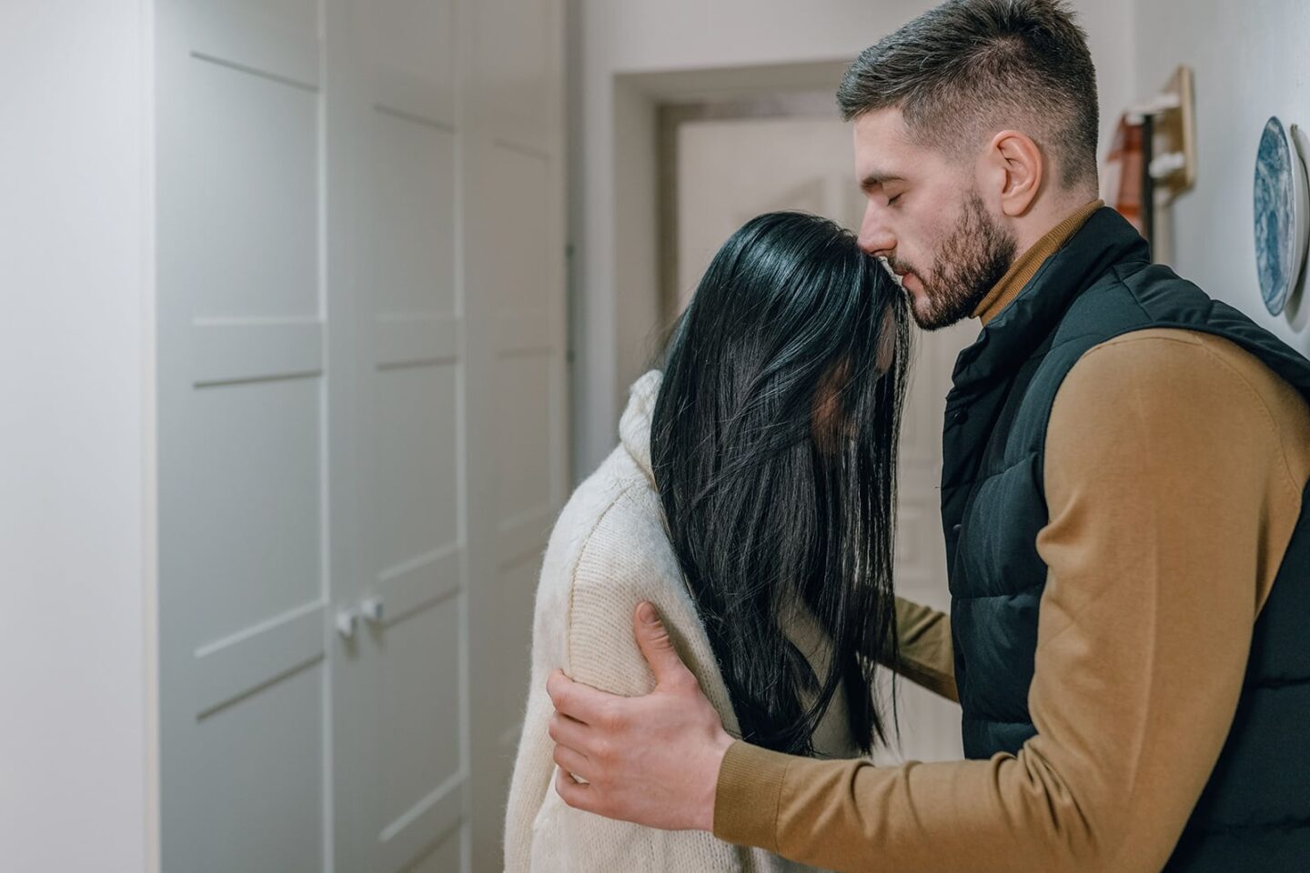 A husband kissing his wife on the forehead with care, taking FMLA to be home and give care