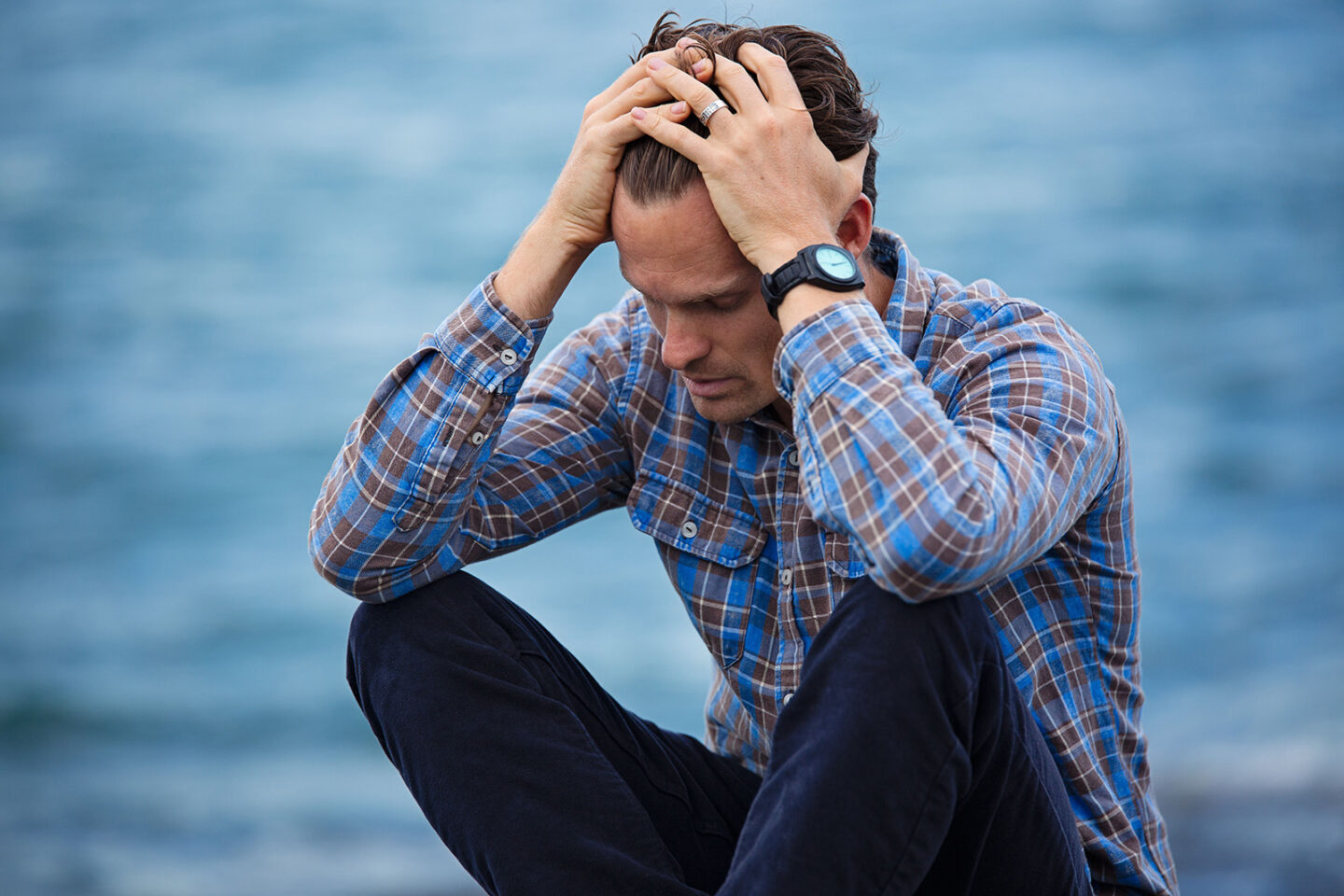 gout in young people, a young man sitting with his head in hands, confused 