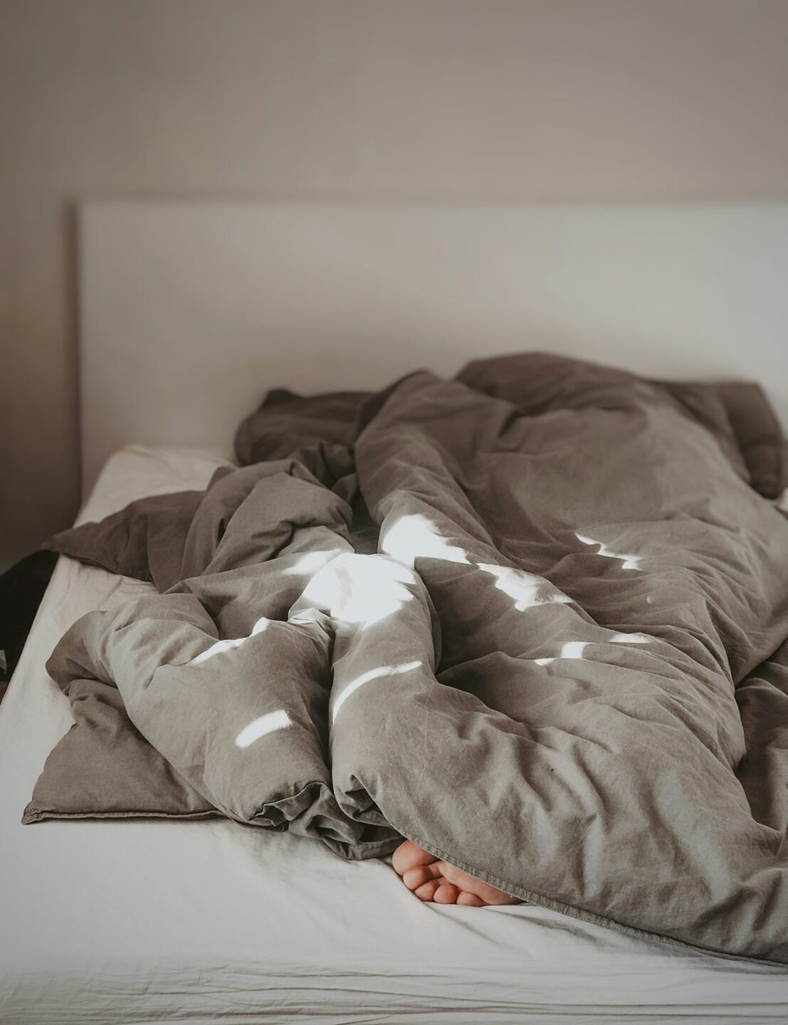 A person in a bed under blankets with just their foot out - Why Do I Keep Getting Gout Flares? 
