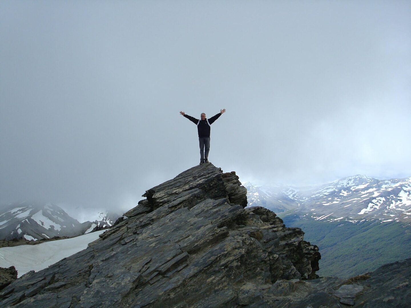 Man with his arms up in happiness on the top of a mountain, celebrating having gout under control