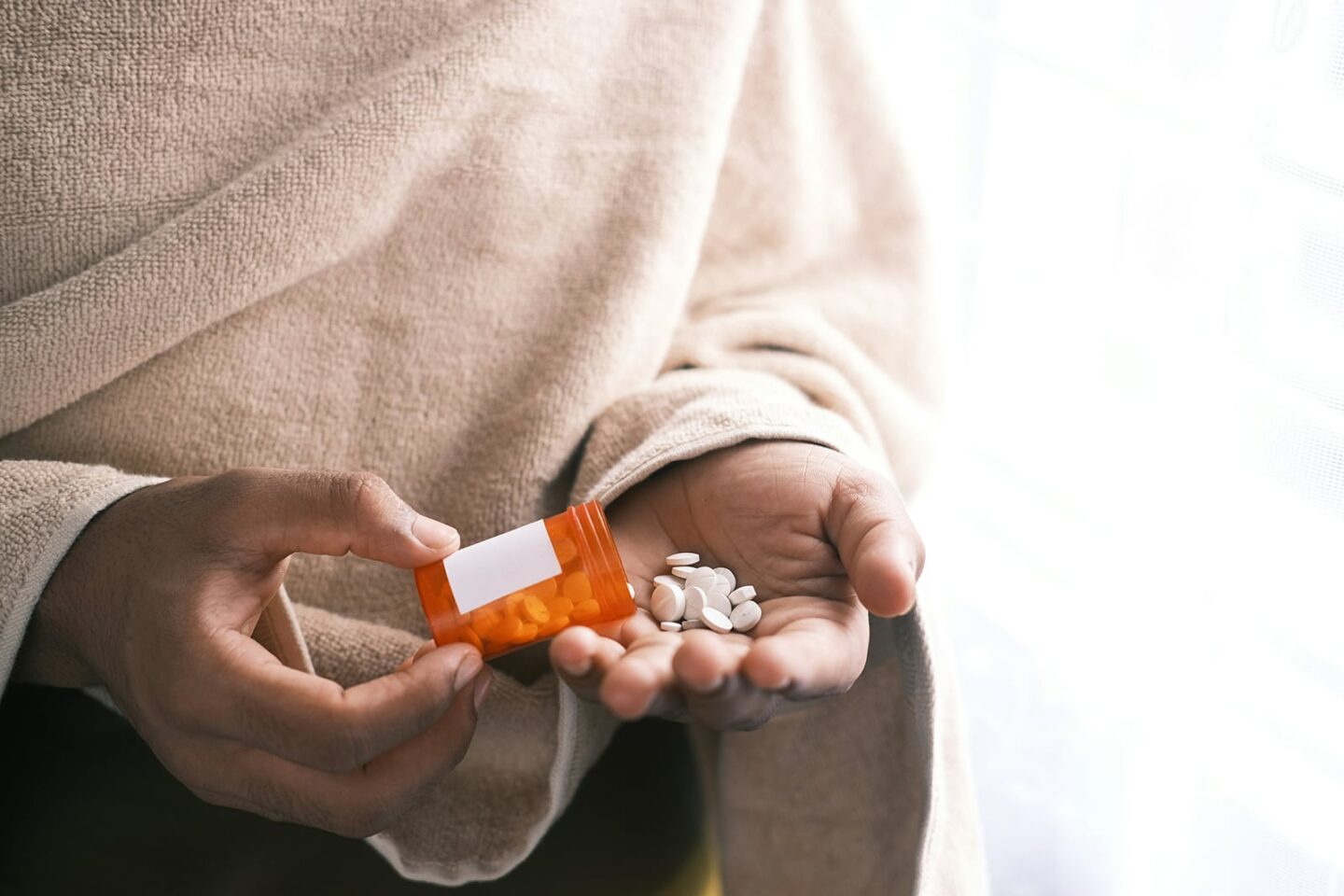 Close up of a woman dumping some white tablets out of a pill container, to get gout under control