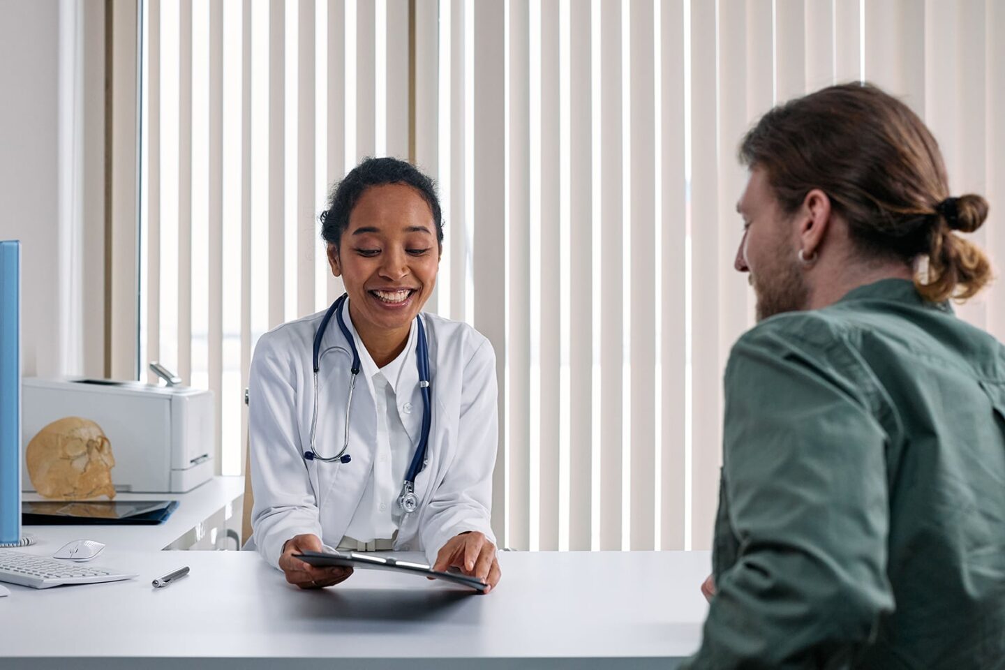 A doctor behind her desk, smiling with a patient, having a gout doctor conversation