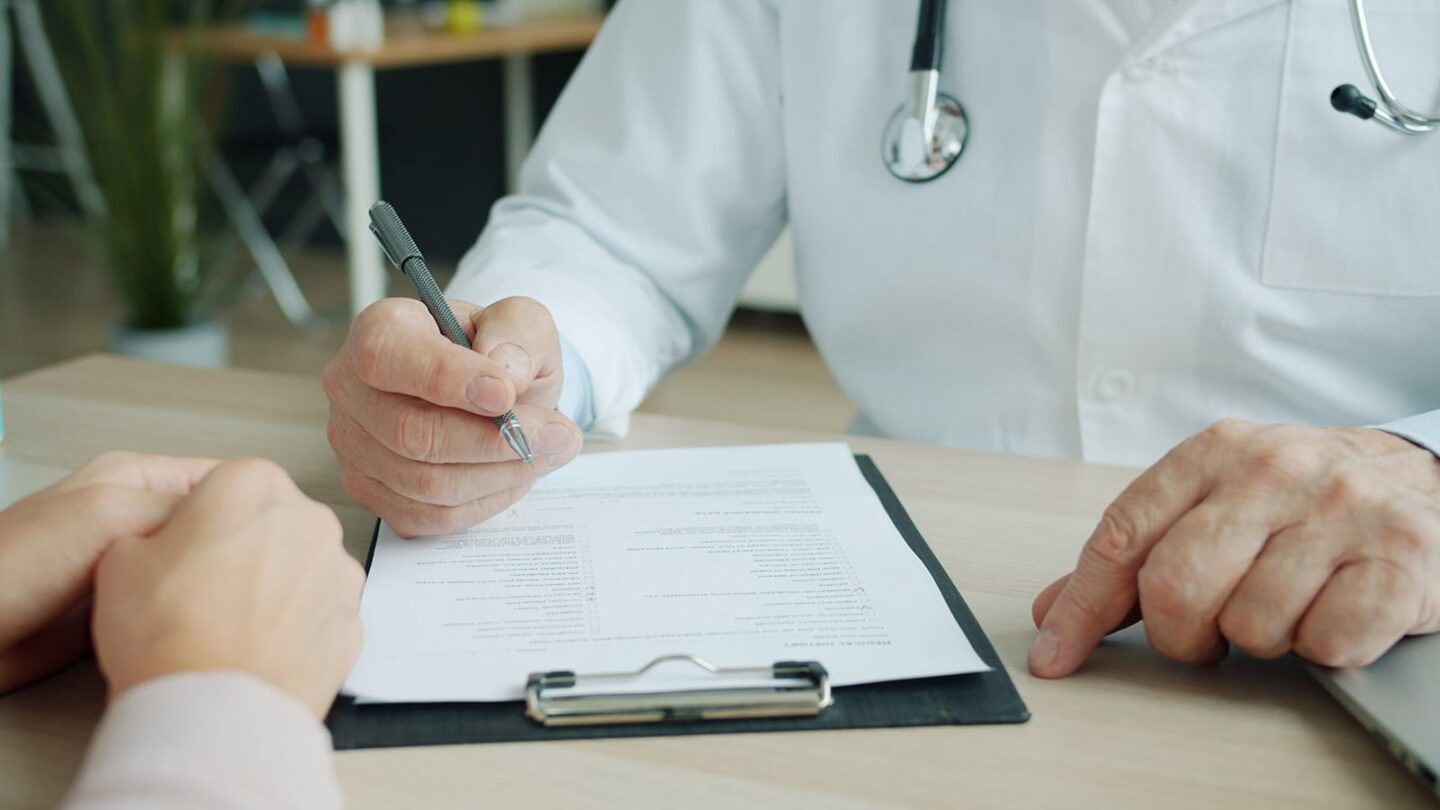 Close up of a gout doctor working working on a form with patient hands shown